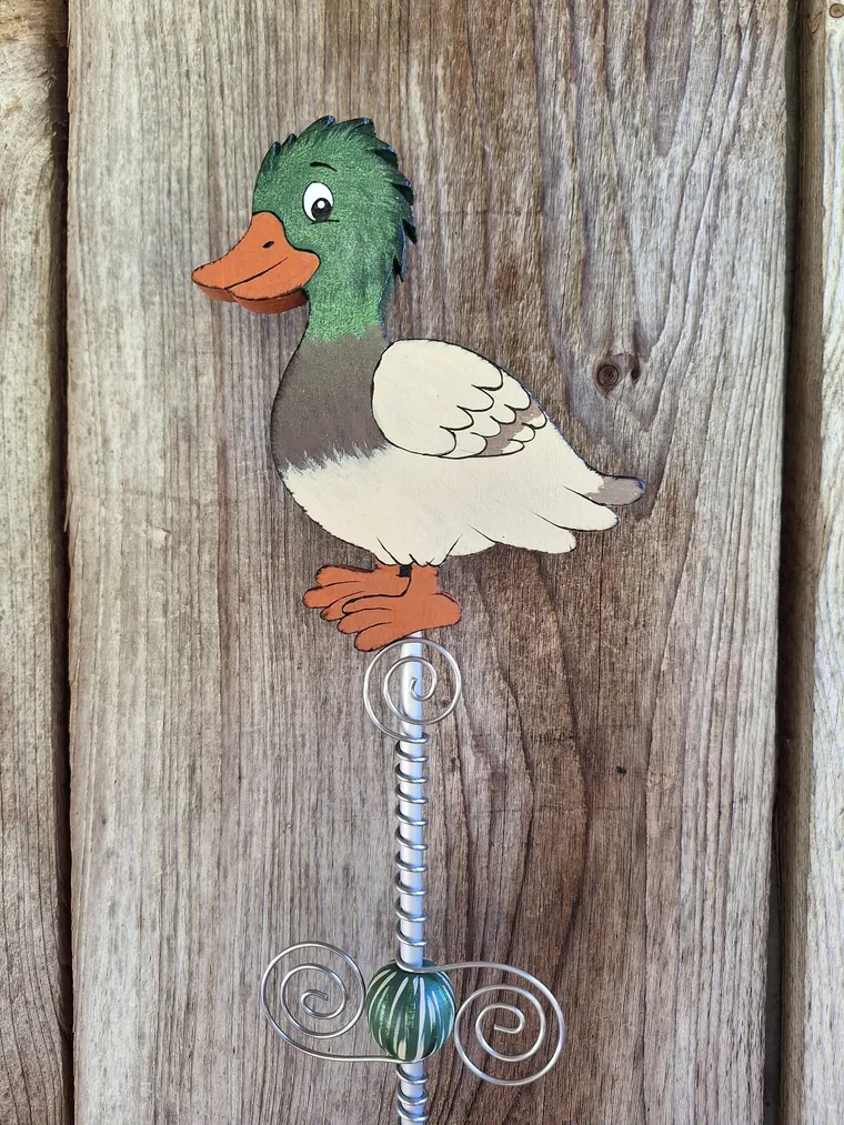 Handbemalte Ente als Gartenstecker vor einer rustikalen Holzwand.