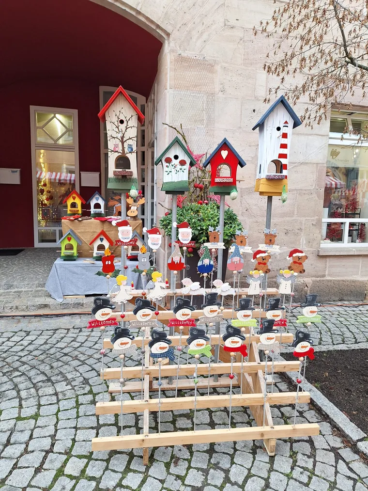 Marktpräsentation mit Vogelhäusern sowie Gartensteckern mit Schneemännern, Weihnachtsmännern und Engeln.