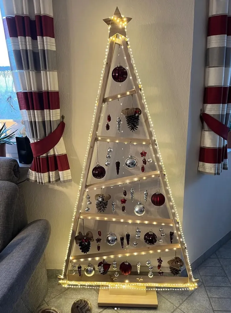 Beleuchtete, dreieckige Holzdekoration in Form eines Weihnachtsbaums mit Kugeln und Zapfen.